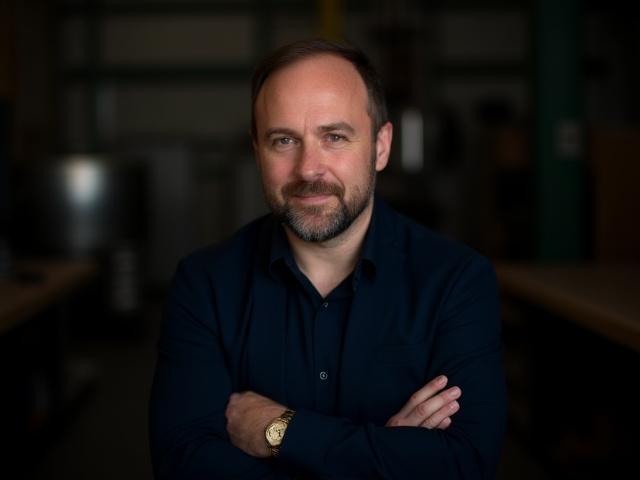 Professionelles Porträt von Max Schmied, dem Gründer und Chef-Ingenieur von Radschmiede, in einer industriellen Umgebung.